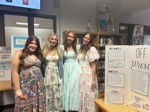 Smiling students stand with school projects