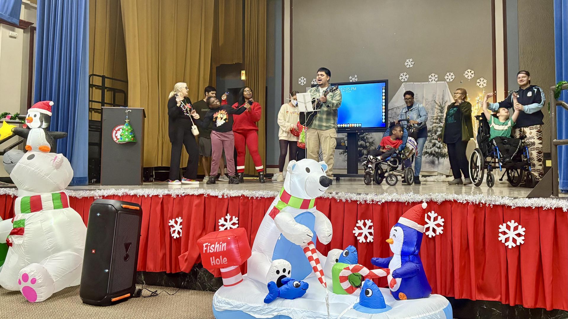 Group performance on stage with festive decorations and inflatable polar bears.