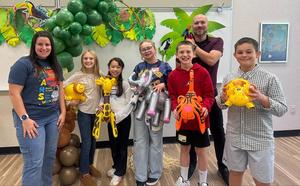 Group of children and adults with animal-themed balloons and decorations.