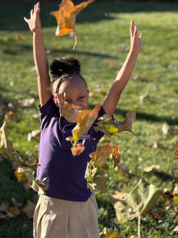 A scholar throws her hands and leaves in the air.