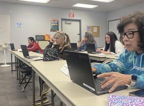 Adult students using chrome book devices in a classroom setting