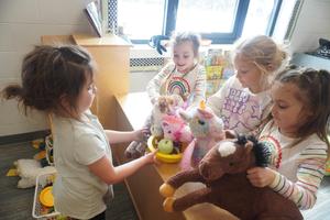 One students gives play food to students for their stuffed animals.