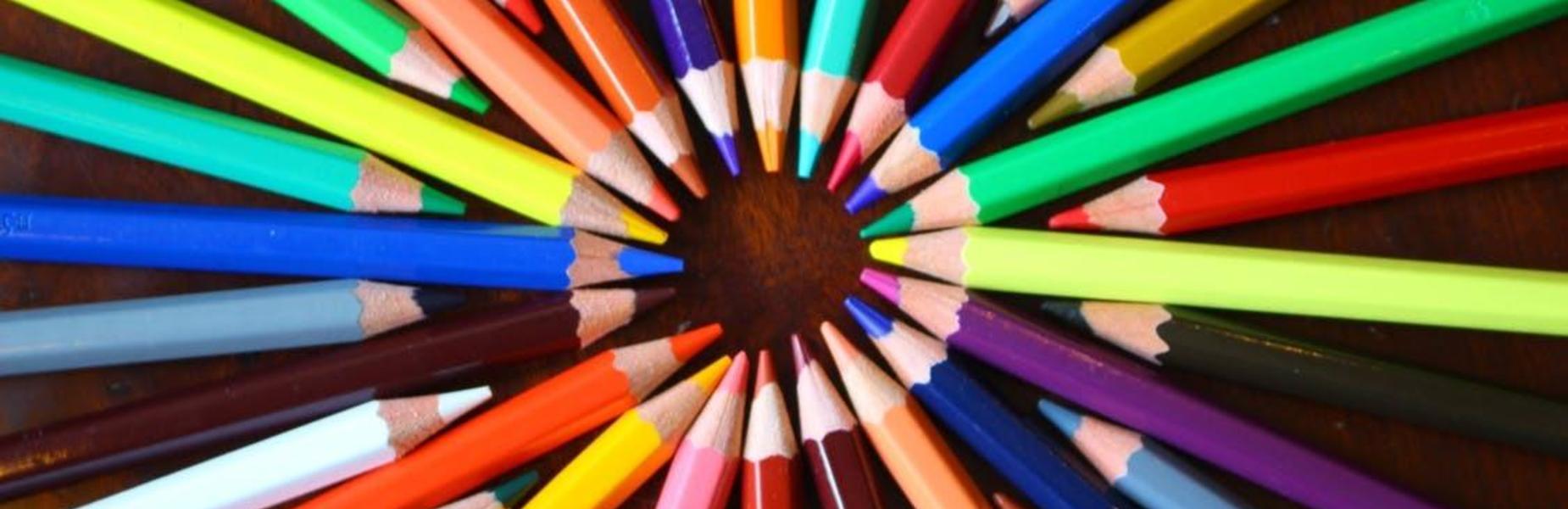 Colorful pencils arranged in a circular pattern on a wooden surface.