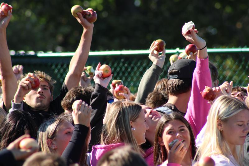 Students hold apples in the air