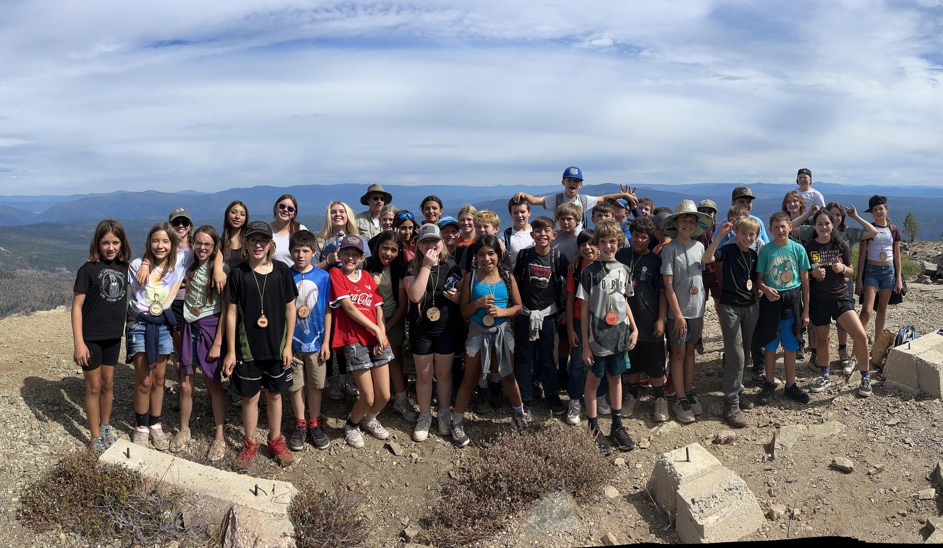 A large group of students poses for a photo high above the valley floor after hiking to Spanish Peak.