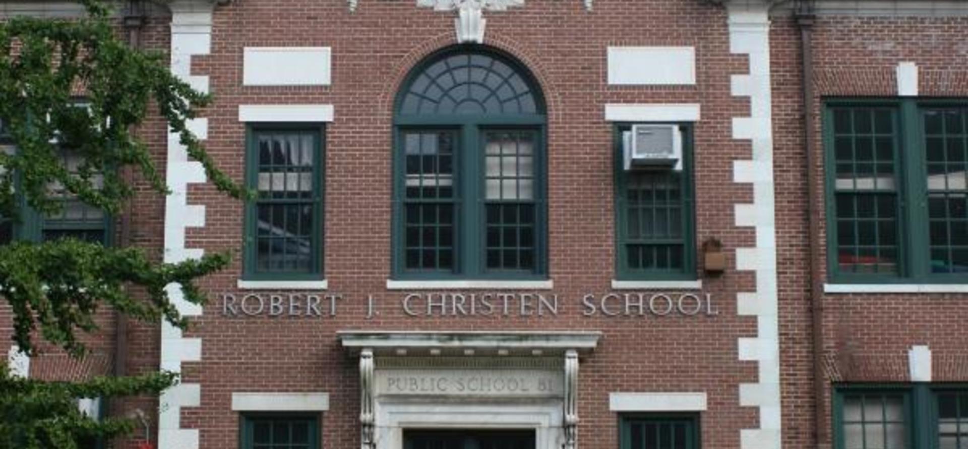 Close-up of school facade featuring name signage and decorative architectural elements.