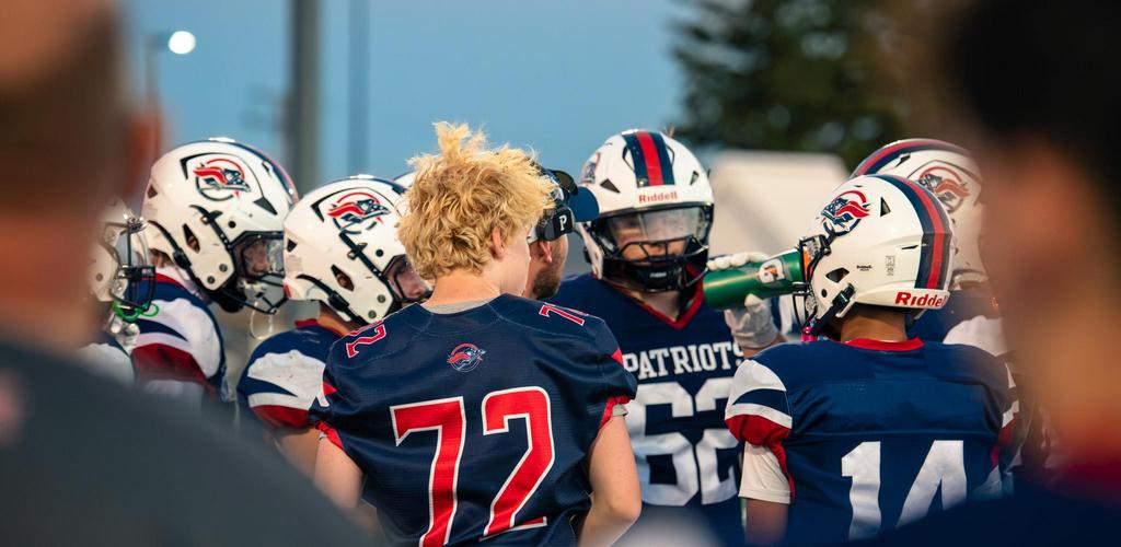 Patriot football players discussing a strategy.