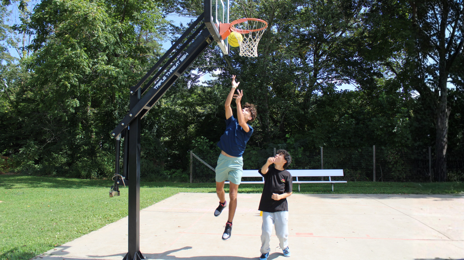 Two students play basketball outside.