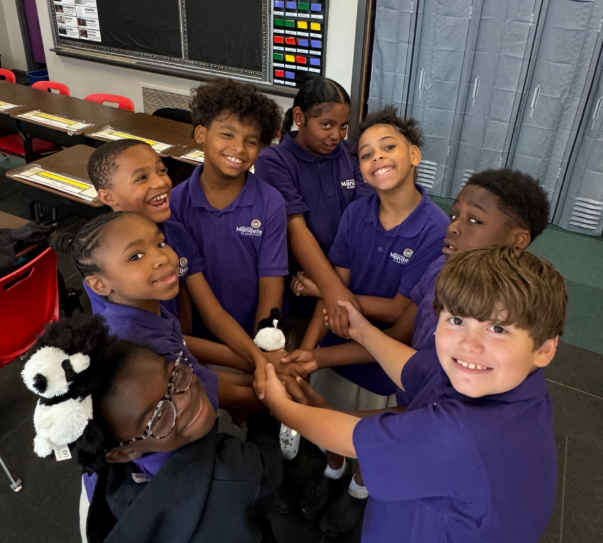 Scholars stand in a circle with their hands in the center