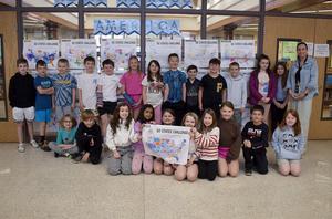 Group of students posing in front of a display featuring a map for a 50 states challenge.