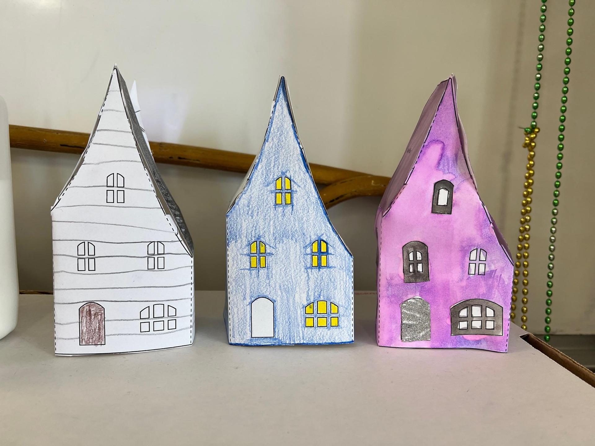 Three decorated paper houses in different colors and designs.