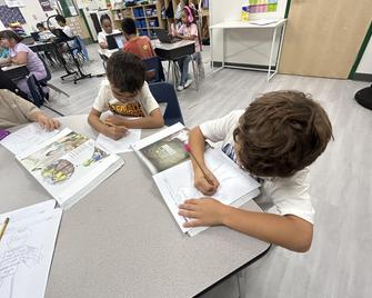 Students engaged in a classroom activity, writing at desks.