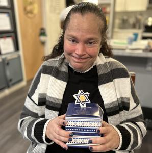 Woman in striped sweater and dark shirt holding blue and white gift box