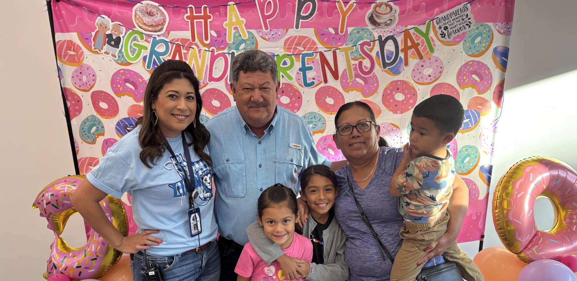A family poses together in front of a colorful donut-themed backdrop.