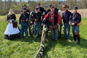9 members of the 4th U.S. Light Artillery Battery F stands in a field with a canon