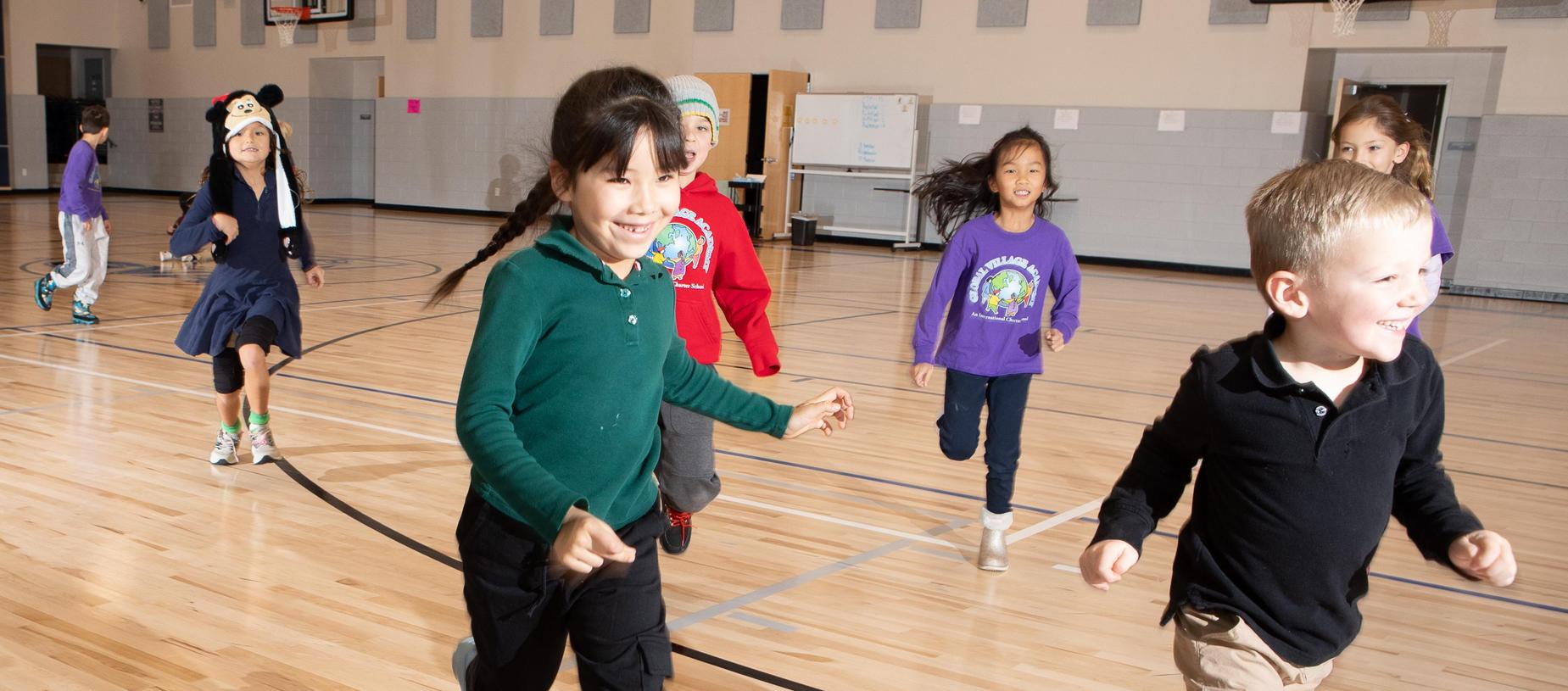 Children running energetically in a gymnasium.