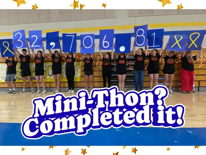 Group of students celebrating with a large monetary total banner in a gym.