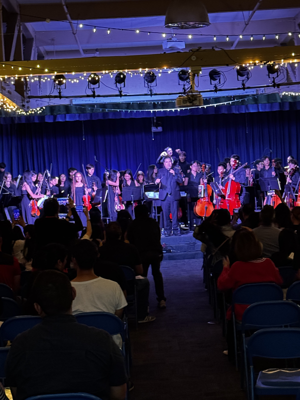 A concert with a full orchestra and audience in a dimly lit venue.