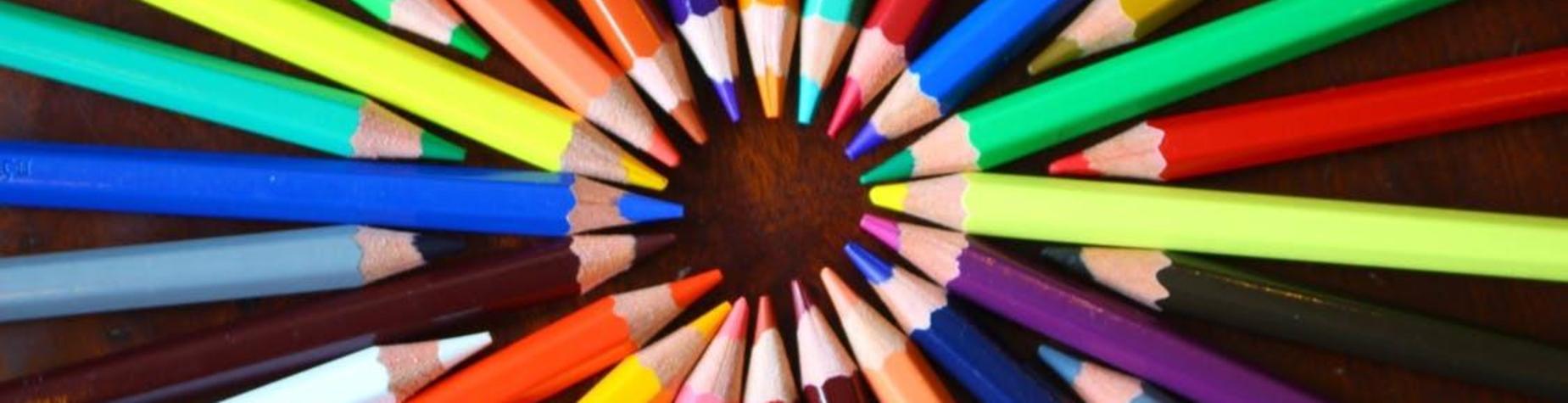 Colorful pencils arranged in a circular pattern on a wooden surface.