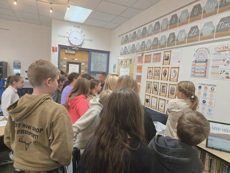 Students gather around the classroom as they examine the clue board.