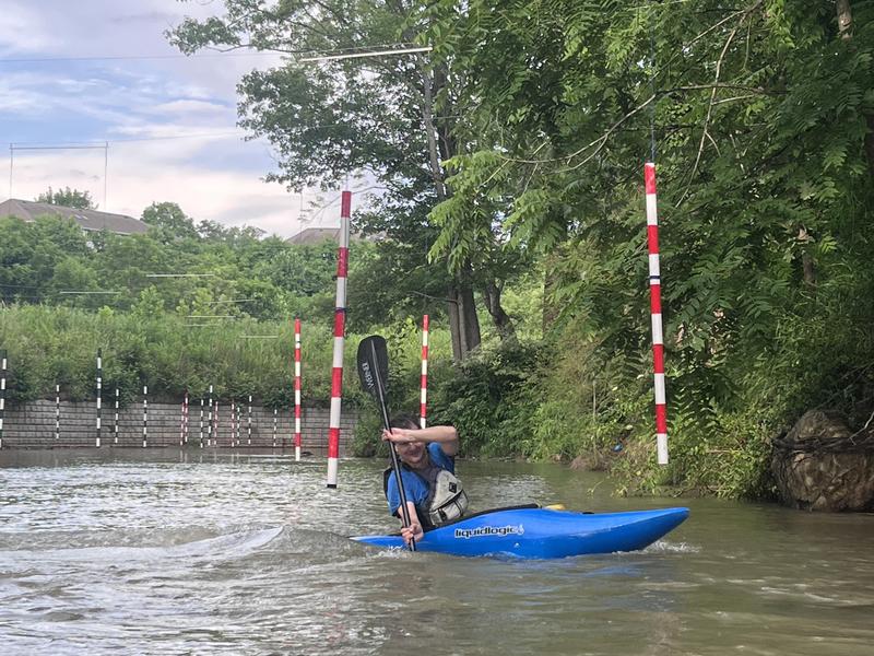A person paddles in a kayak at Hominy Creek on the school campus