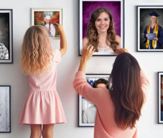 Mother and daughter in pink hanging school photos on a white wall