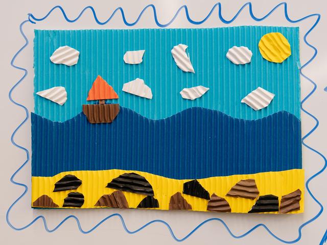Crafted collage of a landscape with waves, a boat, and sun on textured paper.