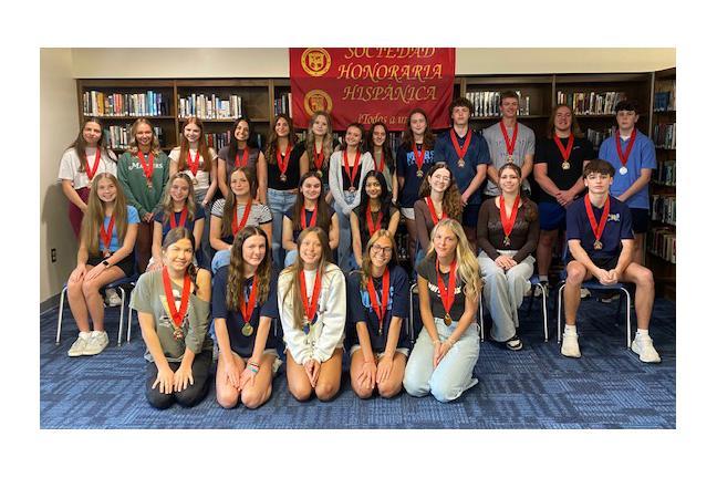 Group of students wearing medals, posing in a library setting.