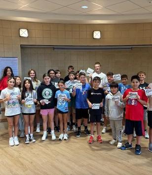 A group of children holding certificates, smiling at Peacock Middle School