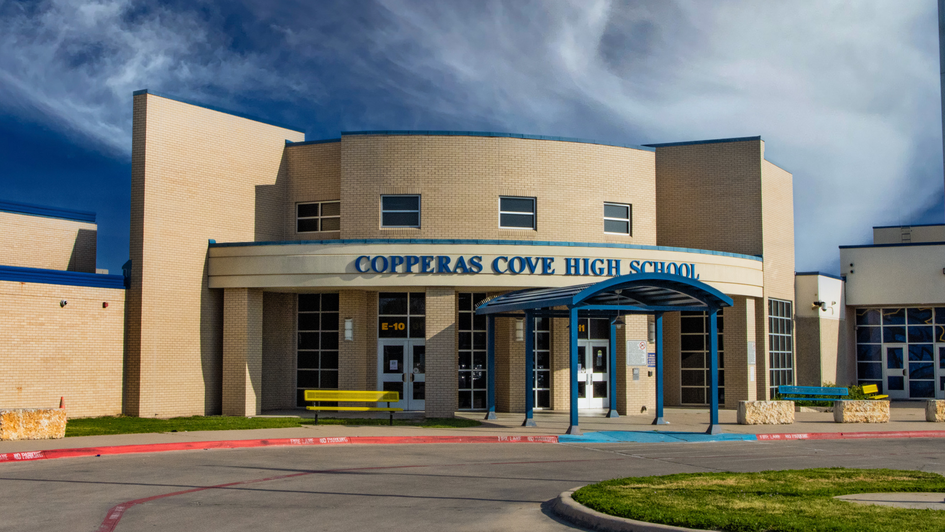 Entrance of Copperas Cove High School with a blue canopy and yellow benches.