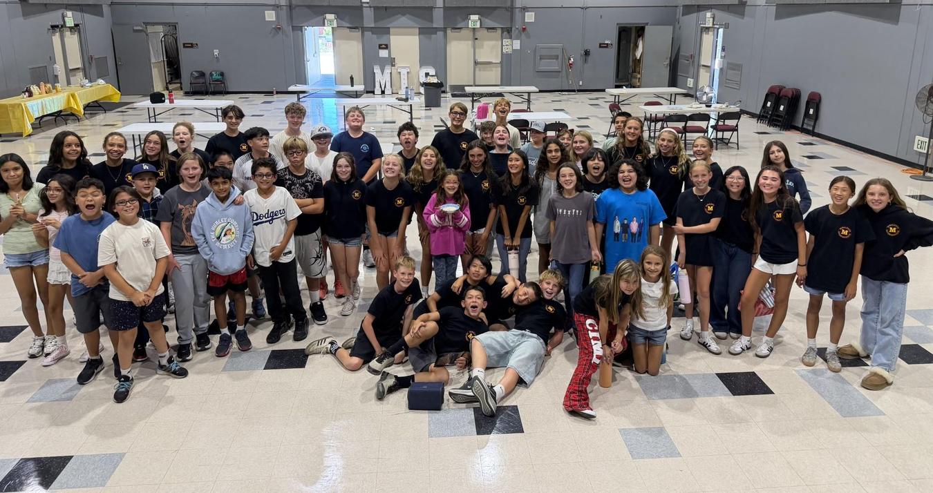A large group of children and teens posing together indoors with smiles.