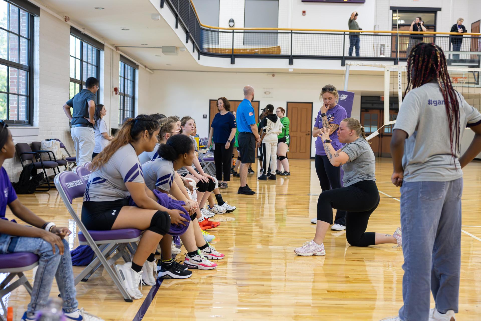 A volleyball team on the sidelines listening to a coach's instructions.