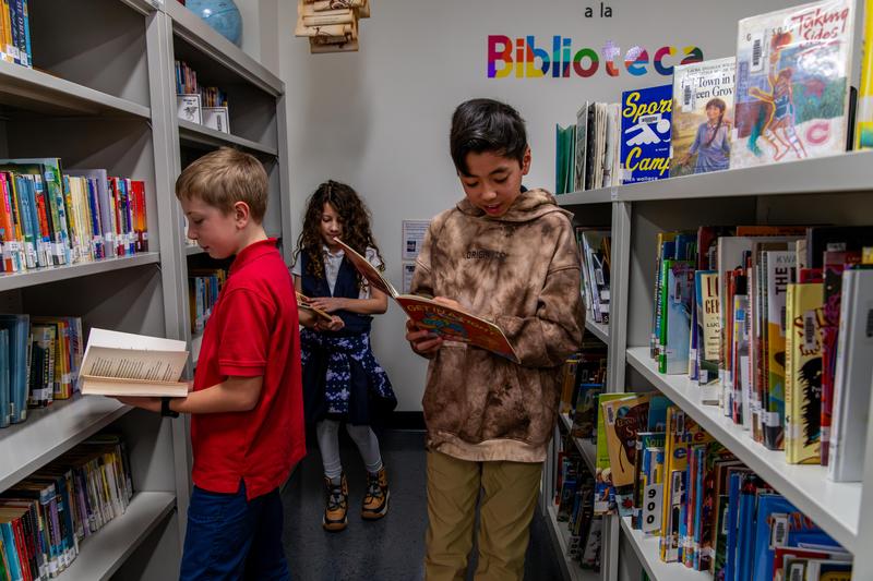 Arco Iris students search for books to read in their school library.