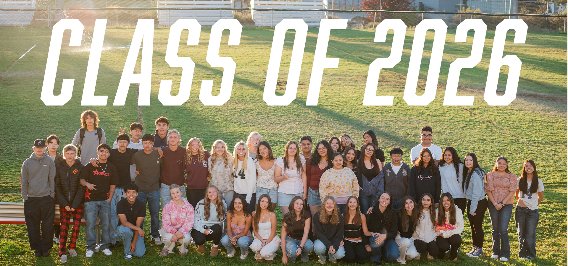 Group photo of the Class of 2026 on a grassy field with a white overlay text.