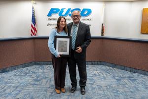Debbie Fleischer holds her Harmony Magnet Academy Classified Employee of the Year award plaque at the PUSD Board meeting.
