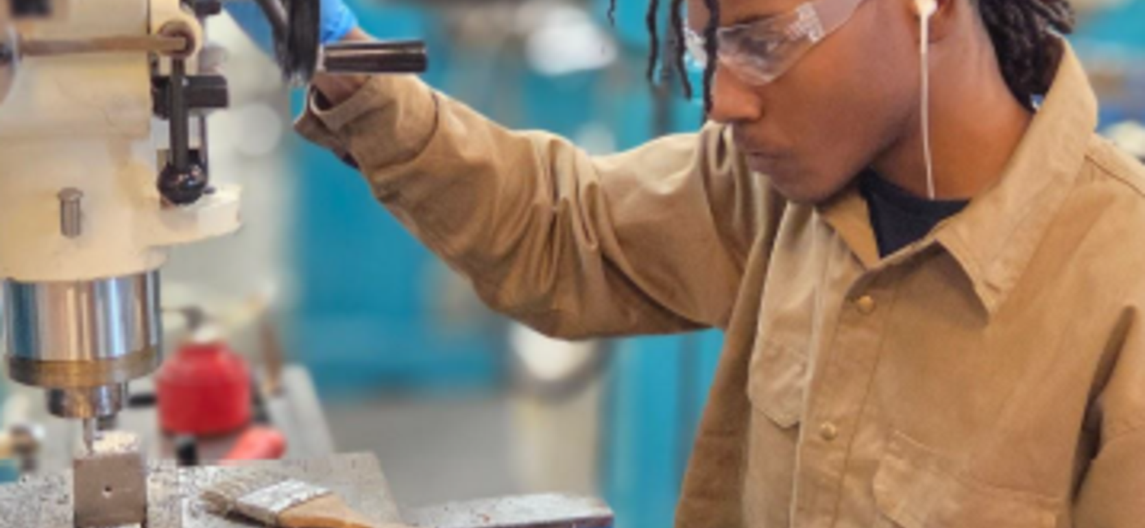 Person using a milling machine in a workshop, focused on the task.