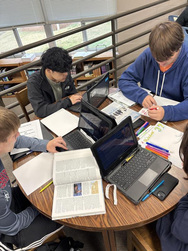 Students working on chromebooks and using books to find info on their element