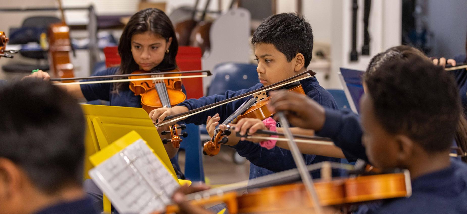 Group of students playing their violins for the next concert