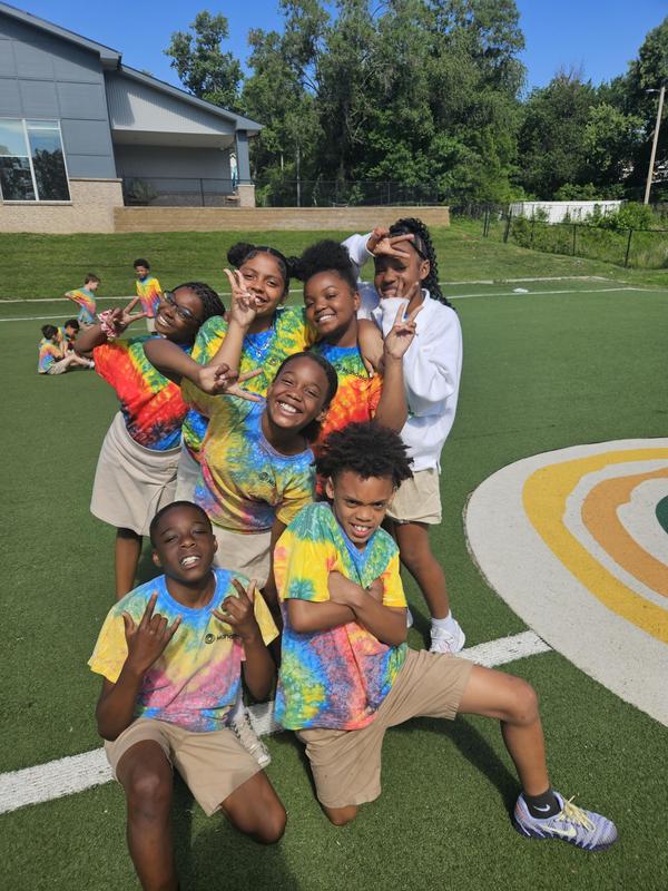 Scholars on the soccer field in tye dye shirts smile for the camera in a group