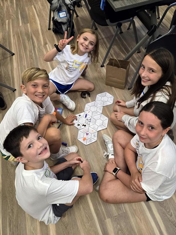 Five children sitting on the floor playing a board game together.