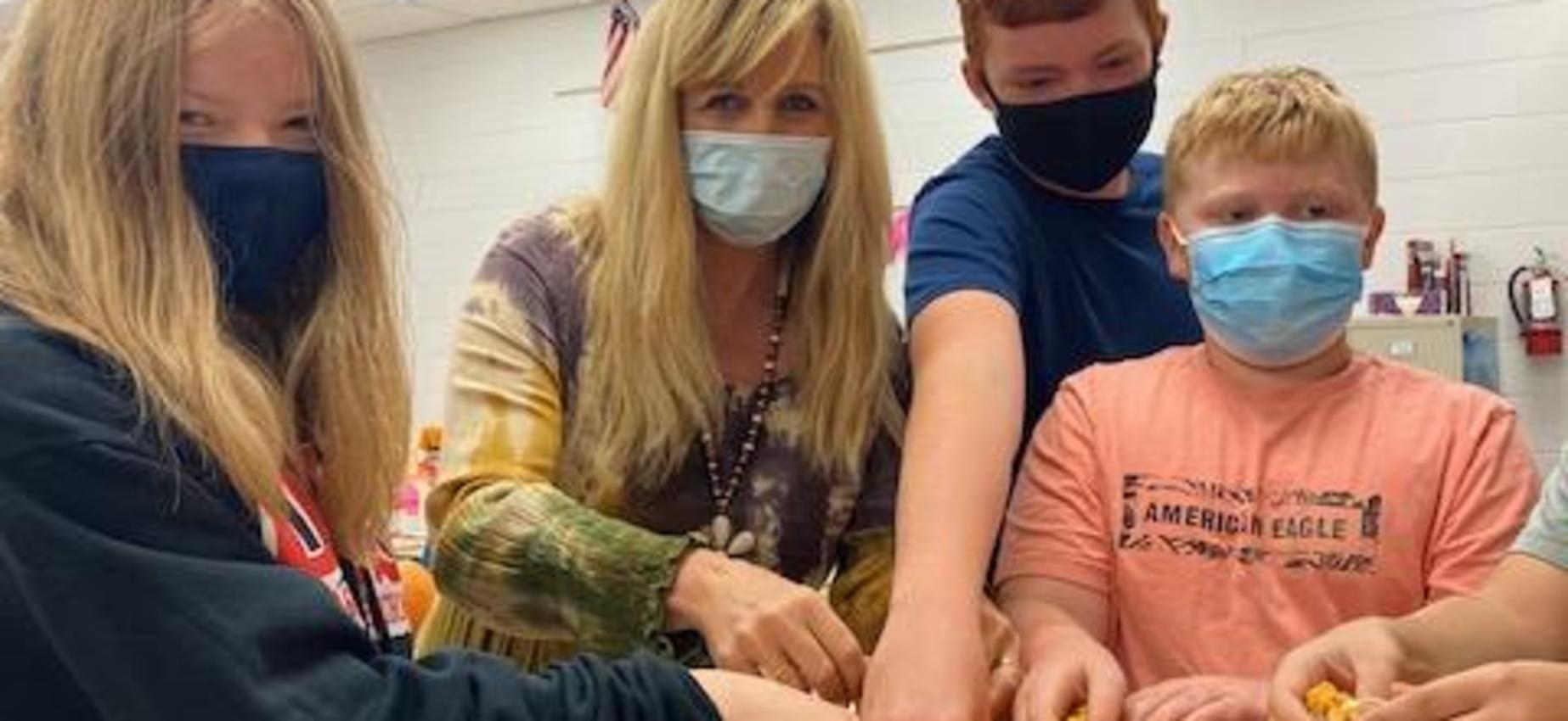 People clean out a pumpkin in a classroom.