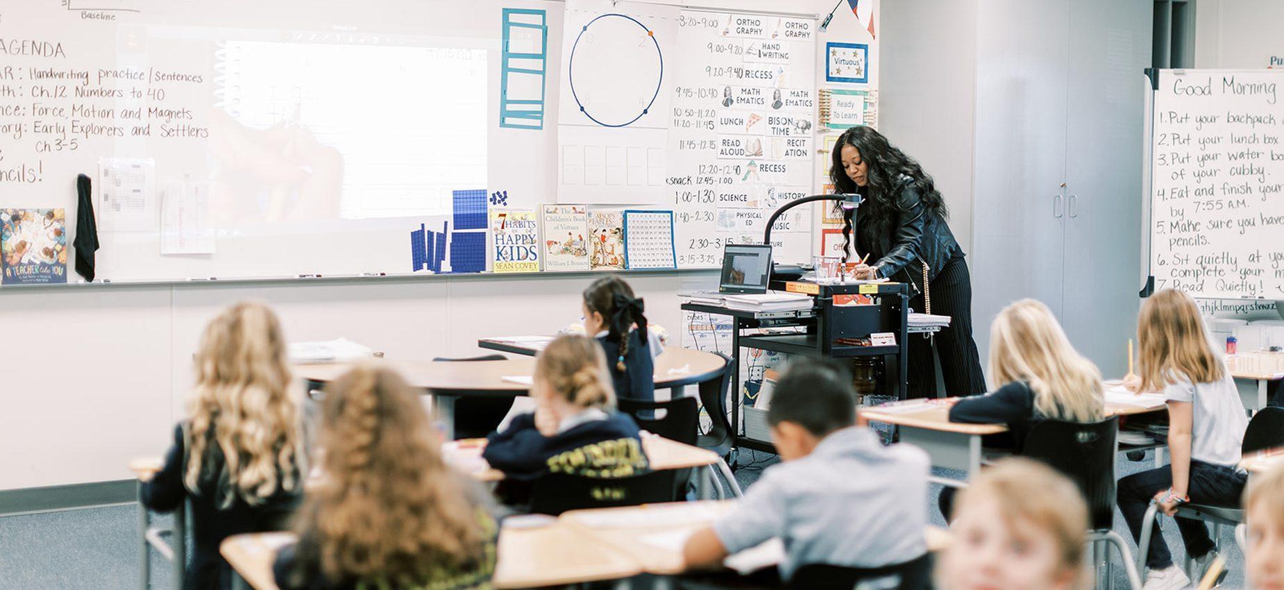 A teacher leads a lesson while elementary students work at their desks at Plainview Classical Academy