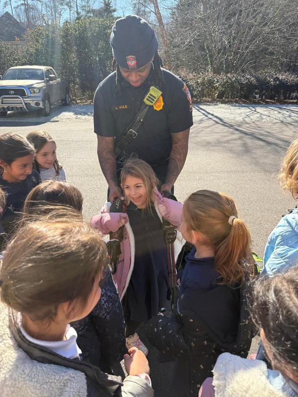 Kindergarten students get to try on an oxygen tank to see how heavy it is
