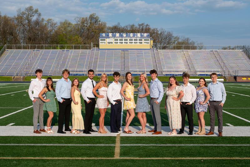members of prom court dressed up standing on football field