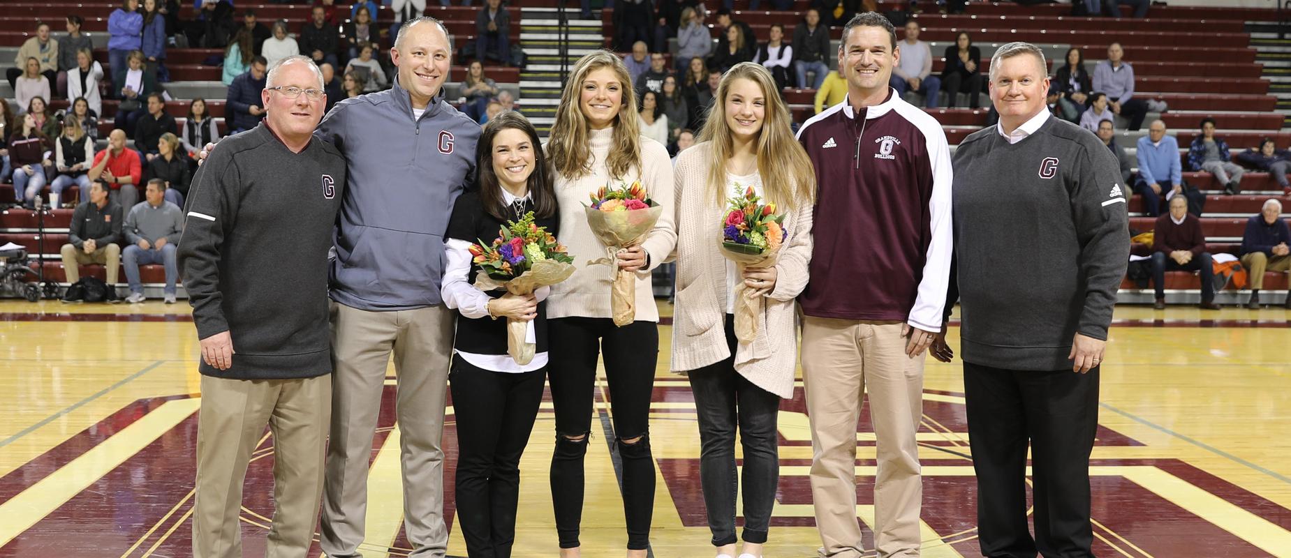 7 people standing in center court with flowers