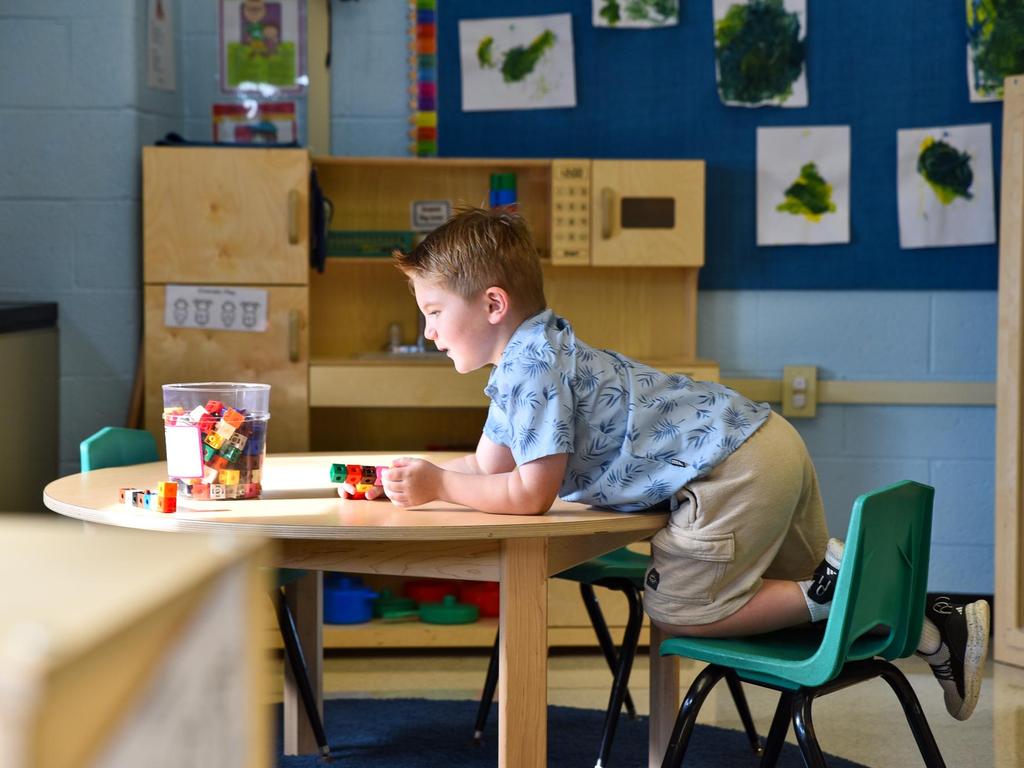 A young student playing with blocks at a table in the classroom.