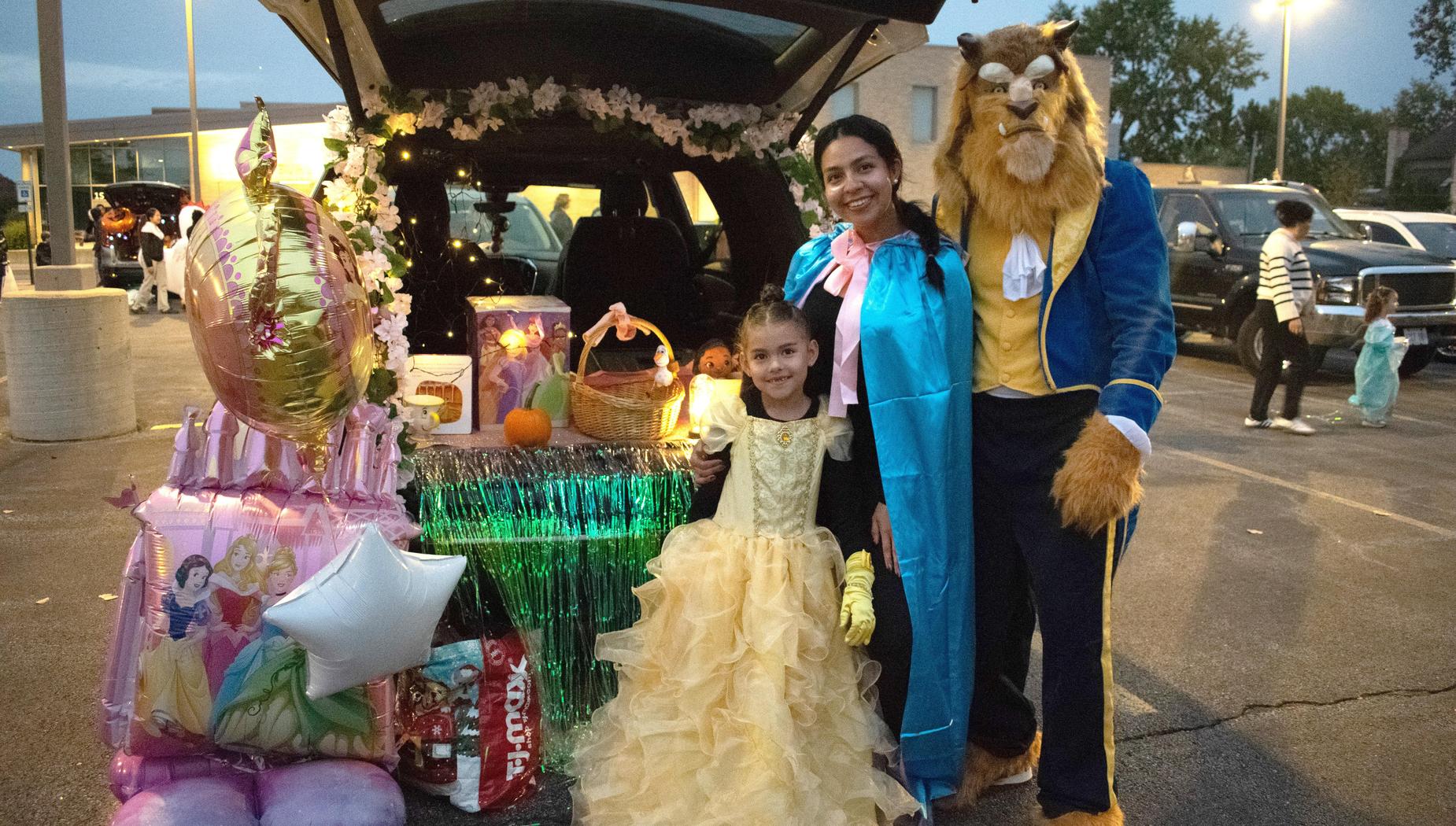 Woman and girl in princess costumes next to a decorated trunk with balloons.