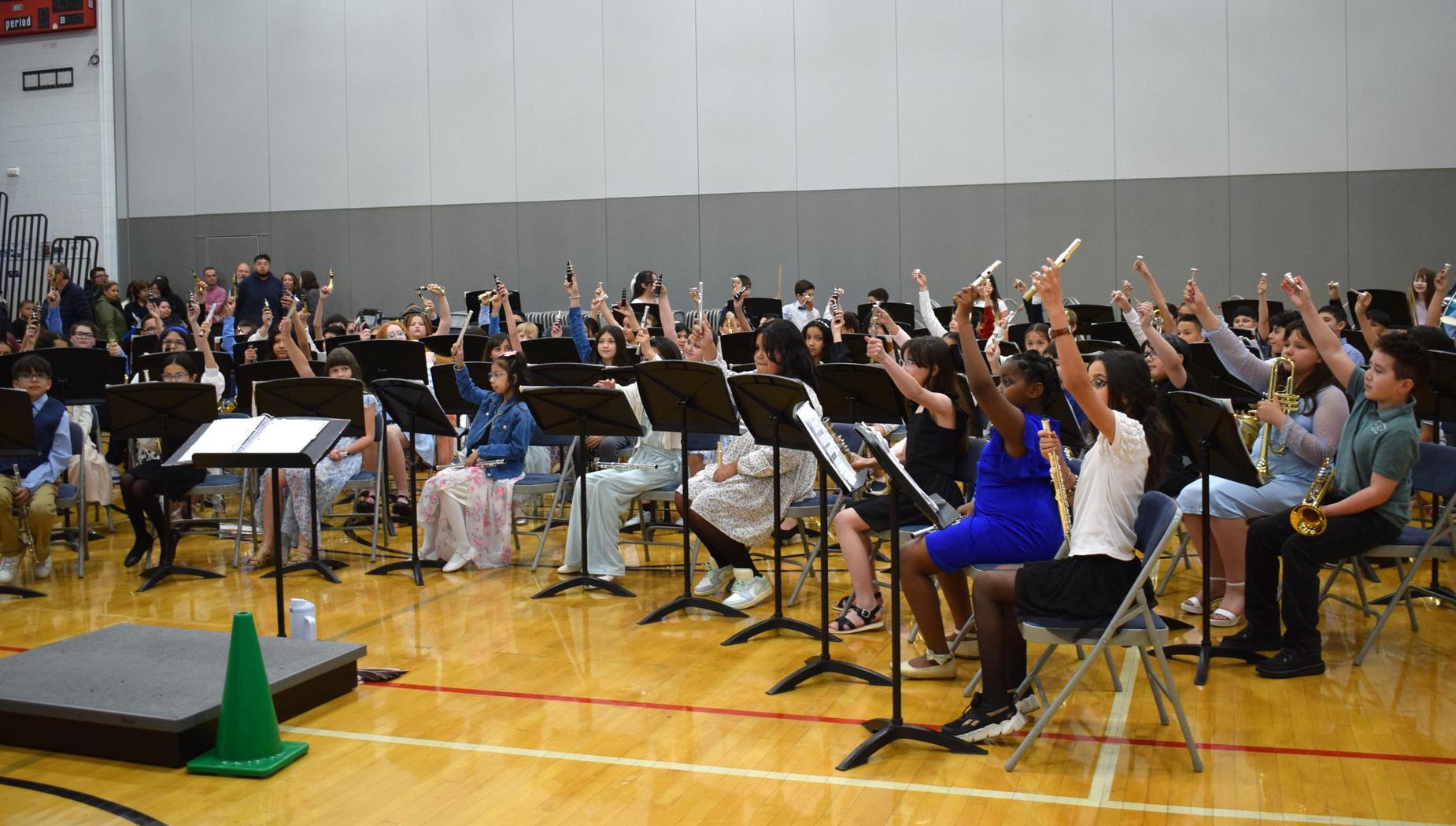 A large group of students seated with raised instruments, ready to perform.