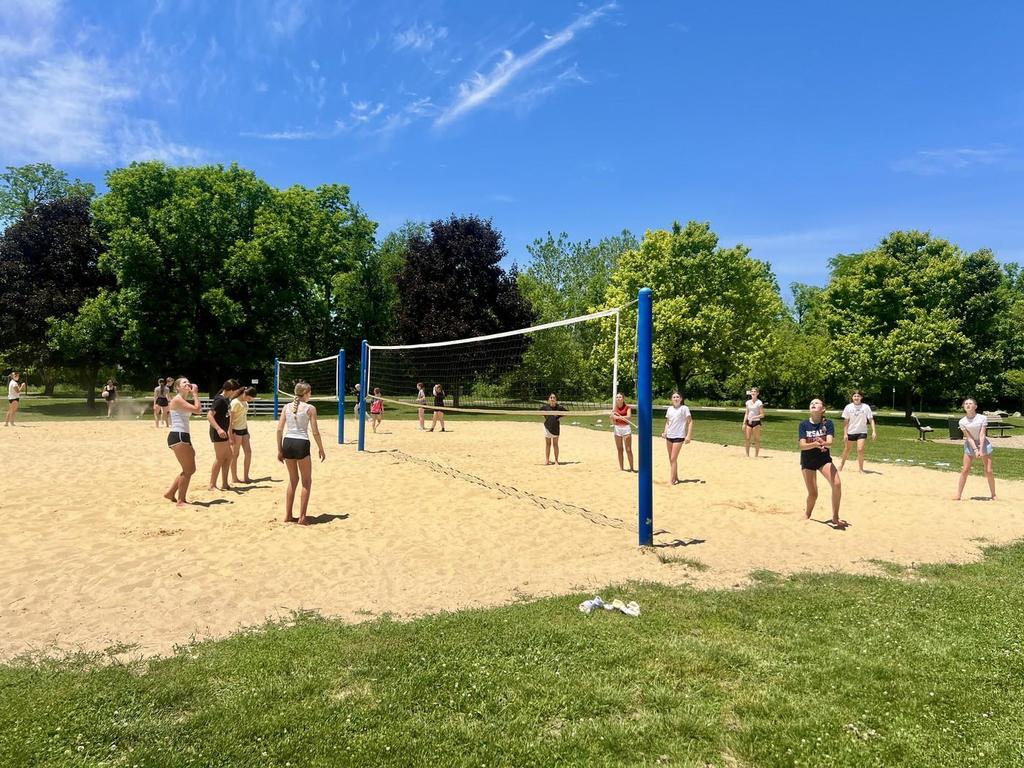 Students playing volleyball outside in the sand.