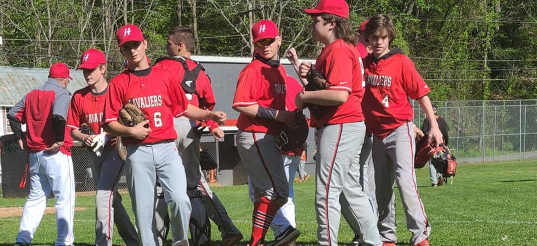 A group of baseball players huddle on a field.